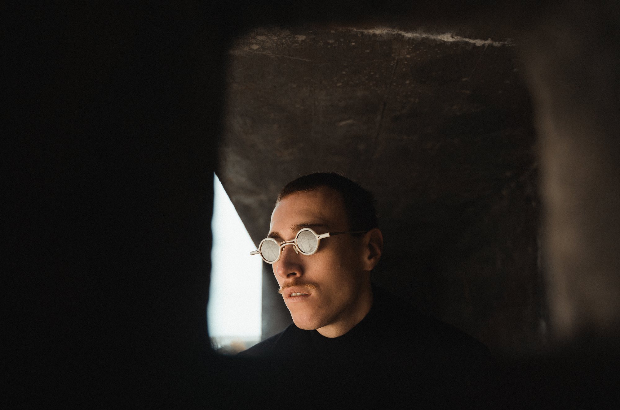 A man with round glasses in window light