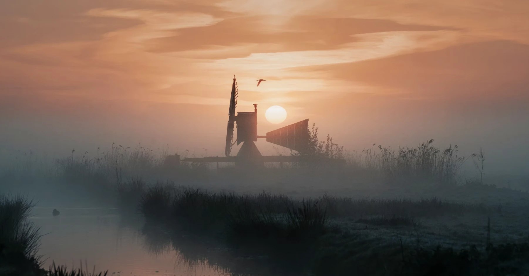 A small windmill in morning fog at sunrise
