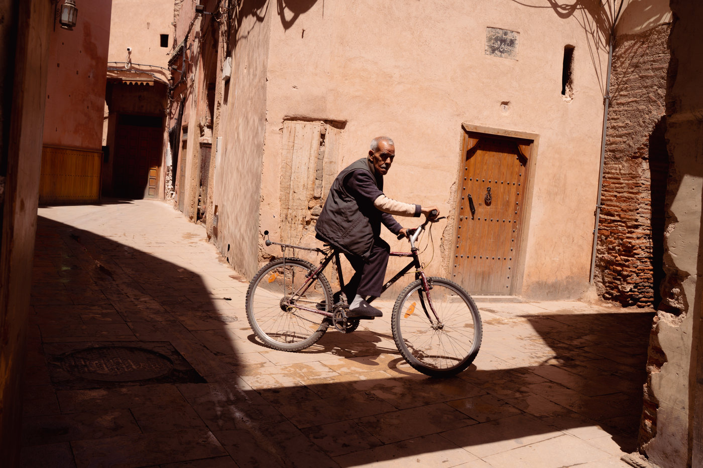 A man cycling through a sunlit alley